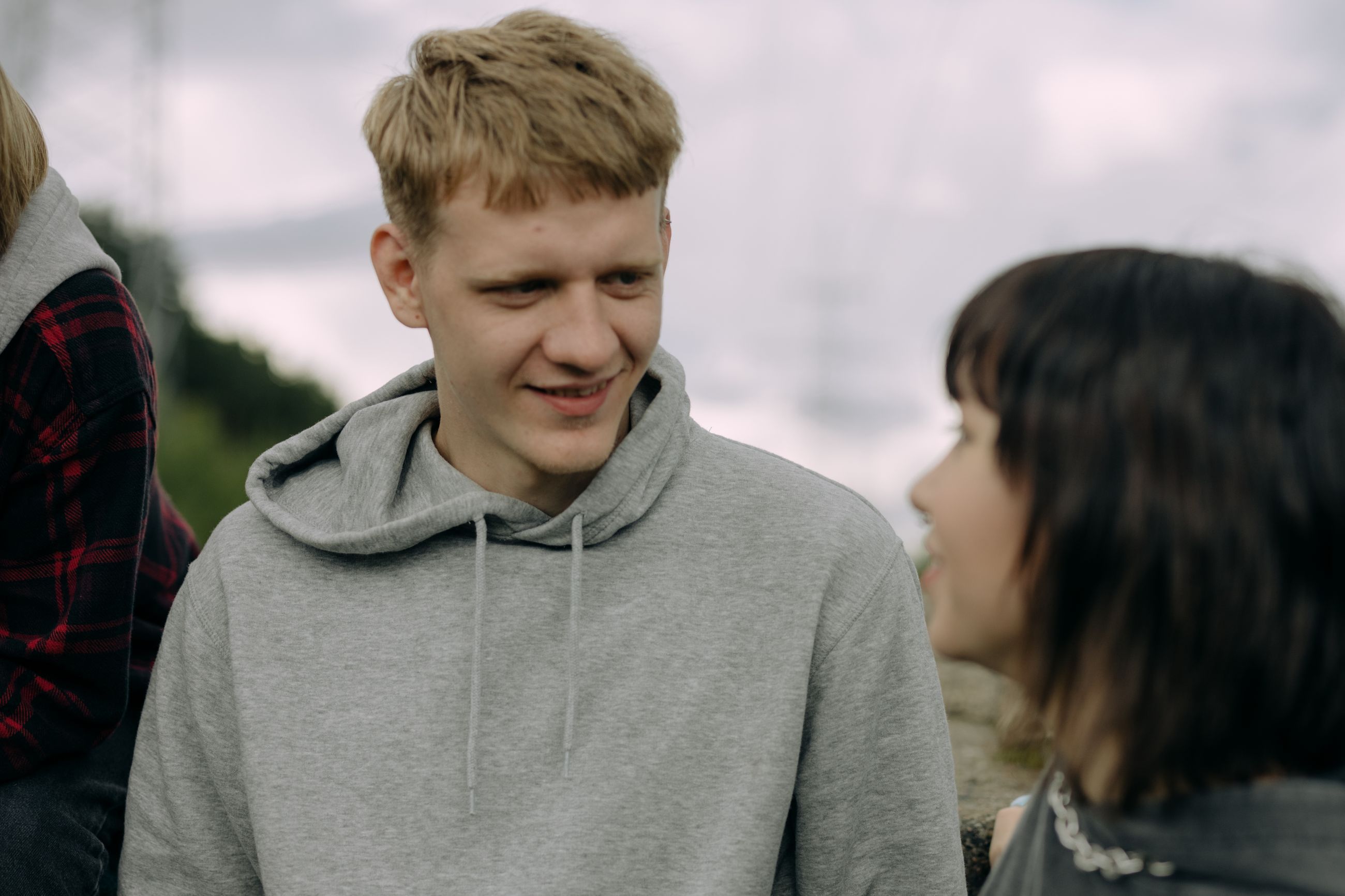 Een jongen in een grijze hoodie is lachend in gesprek met iemand naast hem